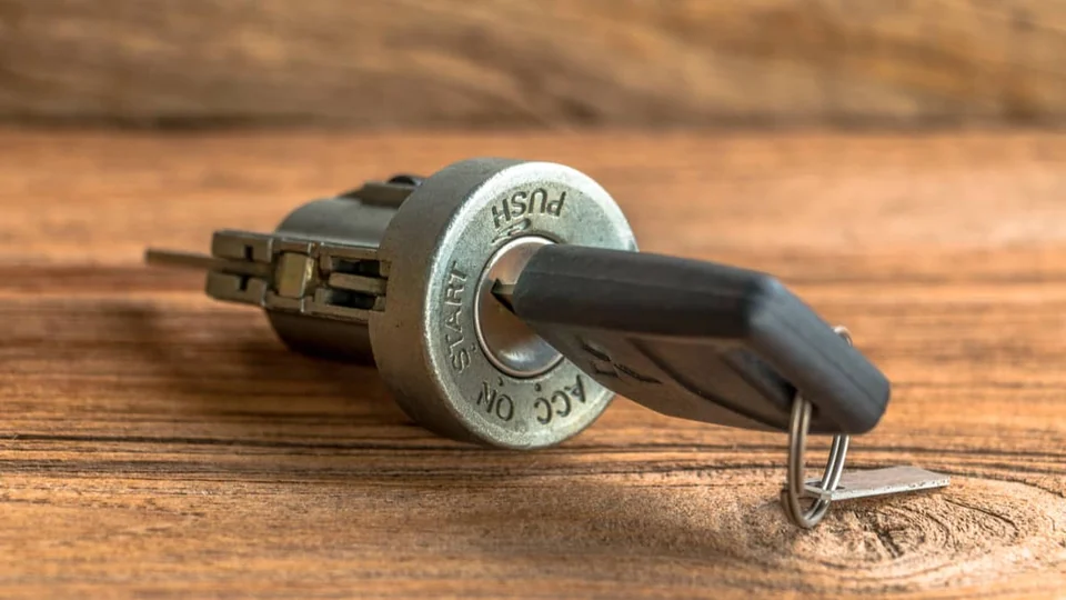 Car key and ignition cylinder on a wooden surface